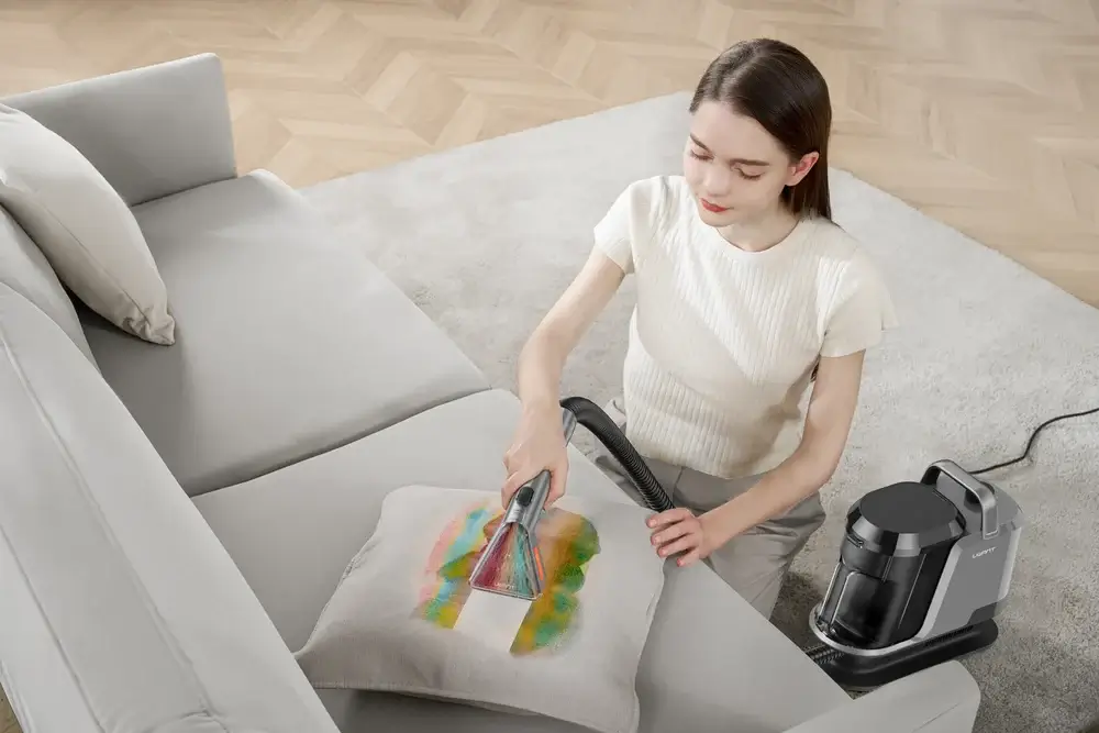 A UWANT fabric cleaner being used on a light upholstered sofa